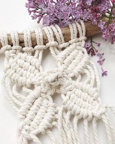 a close up of a piece of rope next to purple flowers on a white surface