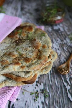 a stack of pita bread sitting on top of a purple towel next to a spoon