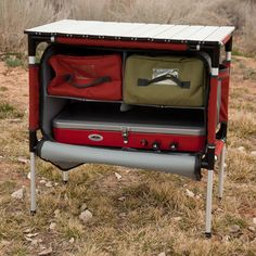 an outdoor stove with two suitcases in it's back compartment on the ground