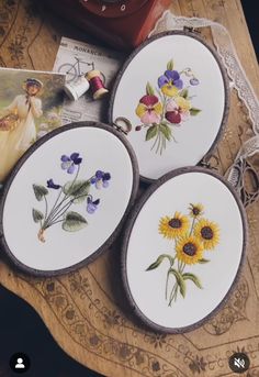 three plates with flowers painted on them are sitting on a table next to a book