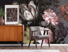 a room with flowers on the wall and a chair in front of it next to a dresser