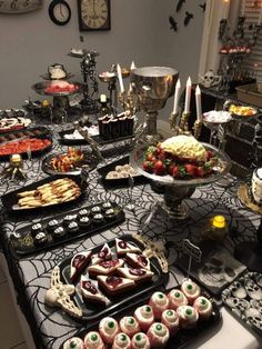 a table topped with lots of food and desserts on top of black lace covered tables