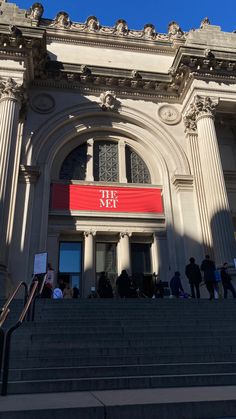 people are walking up and down the stairs to an old building with a red sign on it