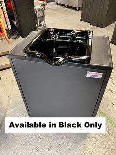 a black dishwasher sitting on top of a floor in a room filled with other items