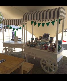 a white cart with green and white flags on it's sides sitting under a tent