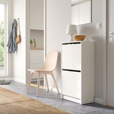 a black chair sitting next to a wooden cabinet in a room with white walls and flooring