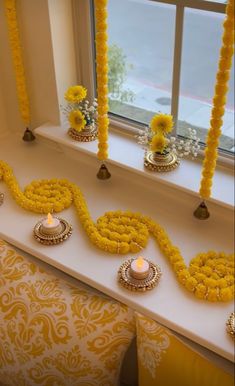 a window sill decorated with yellow flowers and candles for diwaling on the windowsill