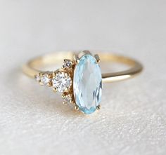 an oval blue topaz ring with three smaller diamonds on the side, set in yellow gold