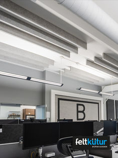 an office cubicle with two computer desks and three monitors