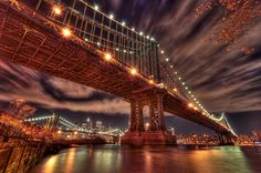 the bridge is lit up at night and it looks like it's going over water