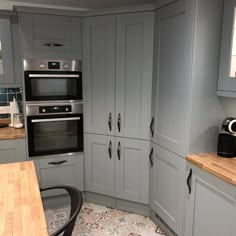 a kitchen with gray cabinets and wooden counter tops, an oven and coffee maker in the corner