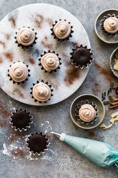 cupcakes with frosting and cinnamon sprinkles on a plate next to other cupcakes