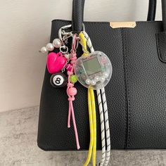 a black purse with some keys attached to it and a cell phone hanging from the handle