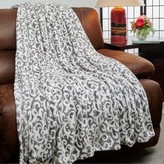 a couch with a blanket on it next to a lamp and vase in the background