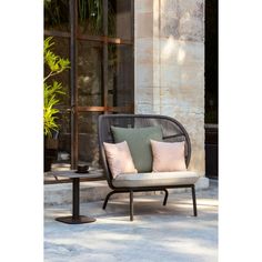 a chair sitting on top of a cement floor next to a plant and window sill