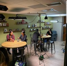 three people sitting at a round table in a room with green walls and pictures on the wall