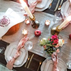 the table is set with white plates, silverware and pink napkins on it