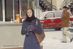 a woman is standing in the snow with her hand on her hip and wearing a scarf