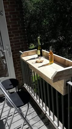 a wooden table sitting on top of a balcony next to a bottle of wine and two bottles