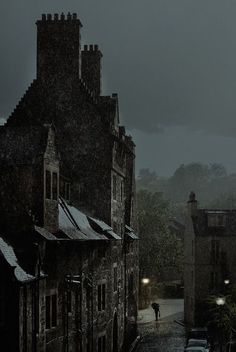 a black and white photo of people walking in the rain on a dark city street