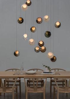 a dining room table and chairs with lights hanging from the ceiling