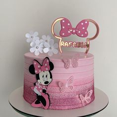 a pink and white cake with minnie mouse on top