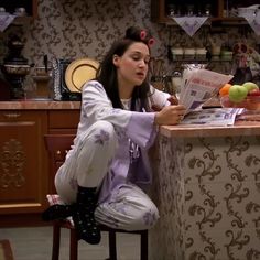 a woman sitting at a kitchen counter reading a paper