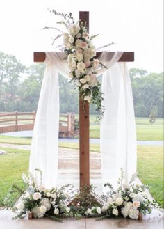 a cross decorated with white flowers and greenery