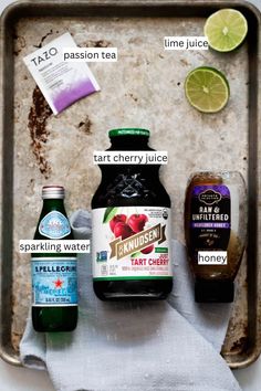 ingredients to make an apple cider recipe laid out on a baking sheet, including apples, lemons, tart and ginger