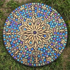 an artistically designed plate sitting on the ground in the grass with green grass around it