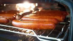 several hot dogs are cooking in an oven