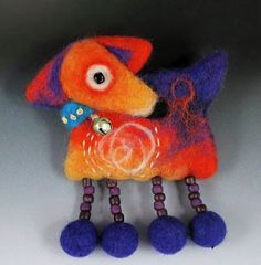 an orange and purple dog with blue balls on it's legs, sitting in front of a gray background