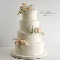 a three tiered wedding cake with flowers on the top and bottom, sitting on a white platter