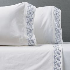 a bed with white sheets and blue trimmings