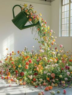 a bunch of flowers that are sitting in the grass with a watering can over them