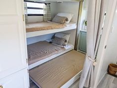 two bunk beds in a small room with curtains on the windowsill and white walls