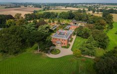 an aerial view of a large house in the middle of trees and grass, surrounded by fields