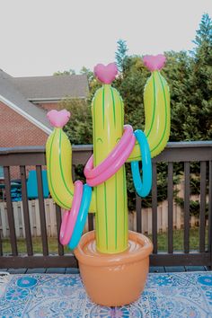 an inflatable cactus sitting on top of a potted plant next to a fence