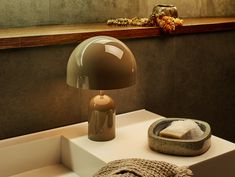 a lamp sitting on top of a table next to a bowl filled with bread and a towel