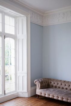 a couch sitting on top of a hard wood floor next to a white door and window