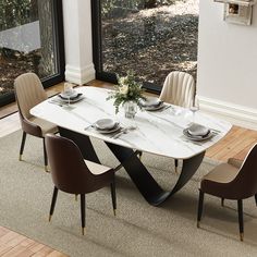 a dining room table with chairs and a vase on the top, in front of a large window