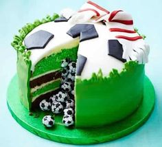 the cake is decorated with soccer balls and green frosting on it's side