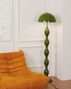 a green lamp sitting on top of a wooden floor next to a yellow chair and ottoman