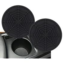 two black spider web coasters sitting on top of a car door sill next to a cup holder