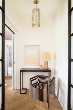 a room with a table, lamp and pictures on the wall next to an open door