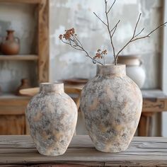 two vases sitting on top of a wooden table next to each other with flowers in them