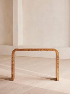 a wooden table sitting on top of a hard wood floor next to a white wall