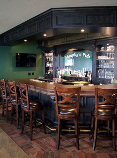 an empty bar with chairs around it and a television on the back wall behind it