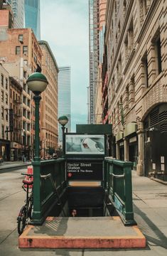 a bike parked on the side of a road next to a green street light and some tall buildings