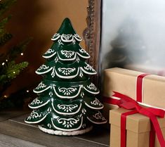 a green ceramic christmas tree sitting next to a box with a red ribbon on it